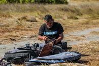 A man preparing his kite surfboard on a sunny day, focusing on getting ready for an adventure.