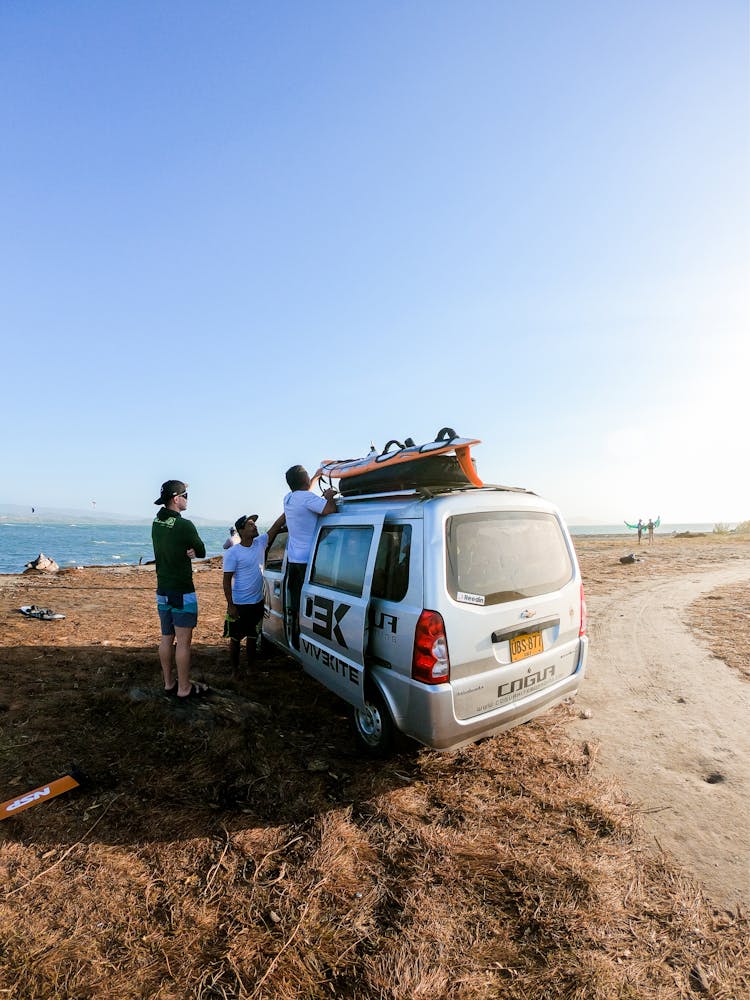 People Standing By A Car With Hydrofoil Board On The Roof 