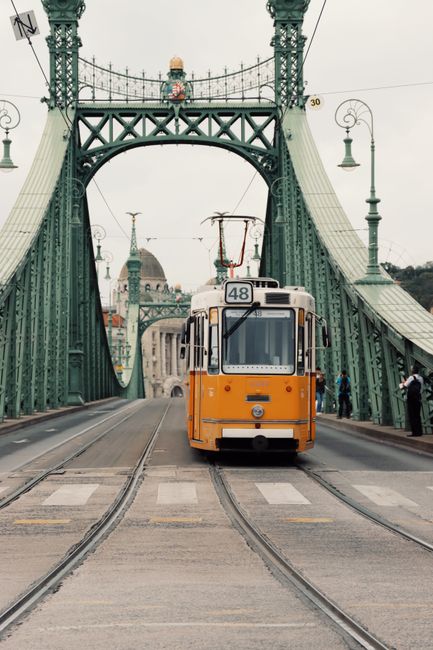 Iconic yellow tram crossing Liberty Bridge in Budapest, Hungary, showcasing urban transport.