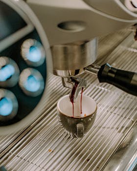 Close-up of espresso brewing into a gray cup in a modern café setting.