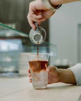 Barista pouring coffee into ice cup at a café in Baku, Azerbaijan.