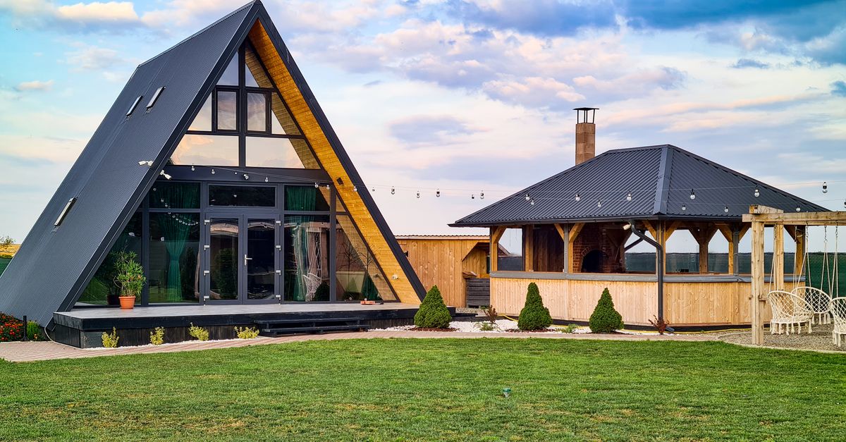 Stylish A-frame cabin and wooden gazebo in a lush summer setting, perfect for vacation retreats.