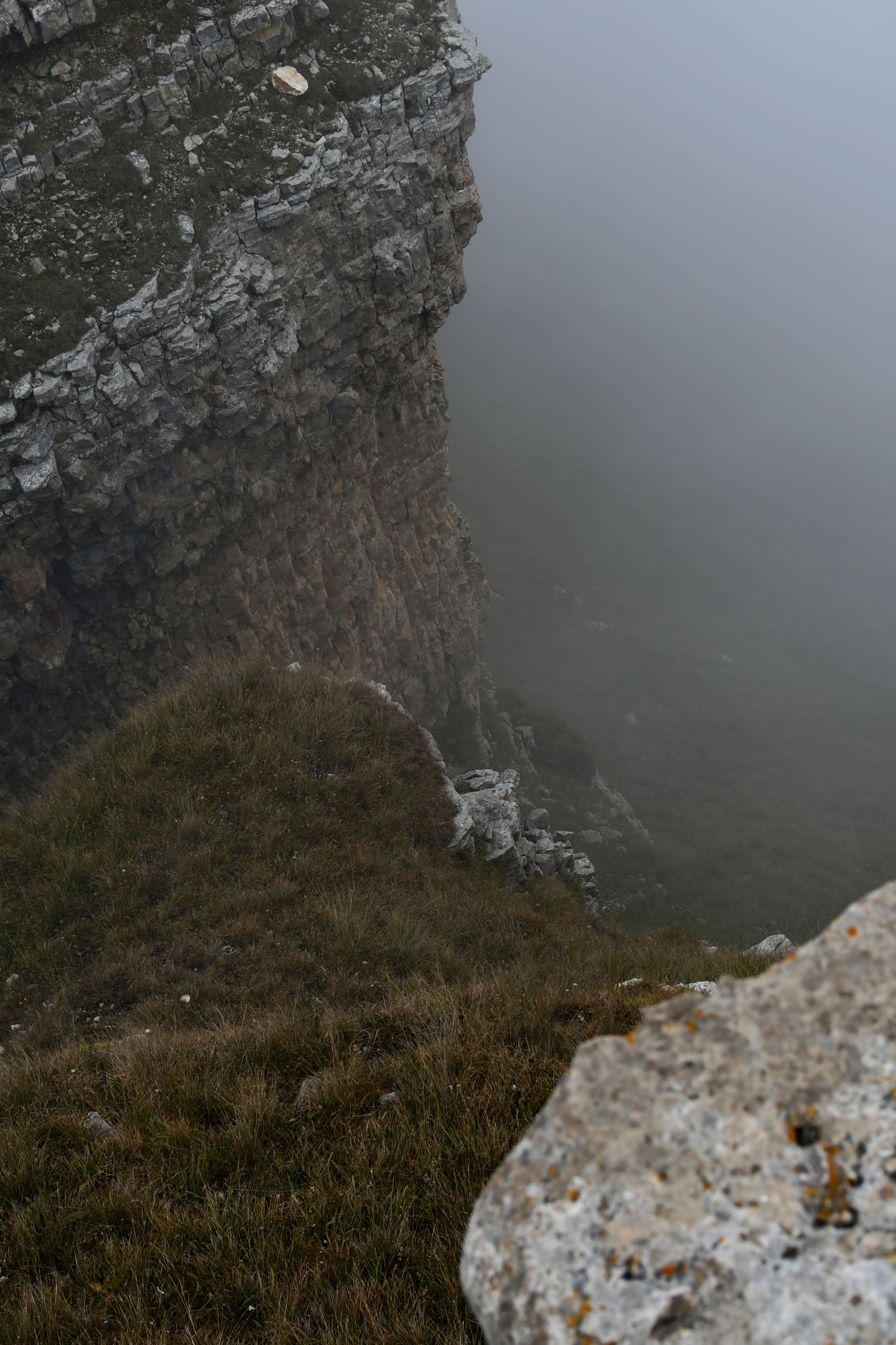 High angle view of a foggy cliffside showcasing eroded rocks and thick mist enveloping the valley.