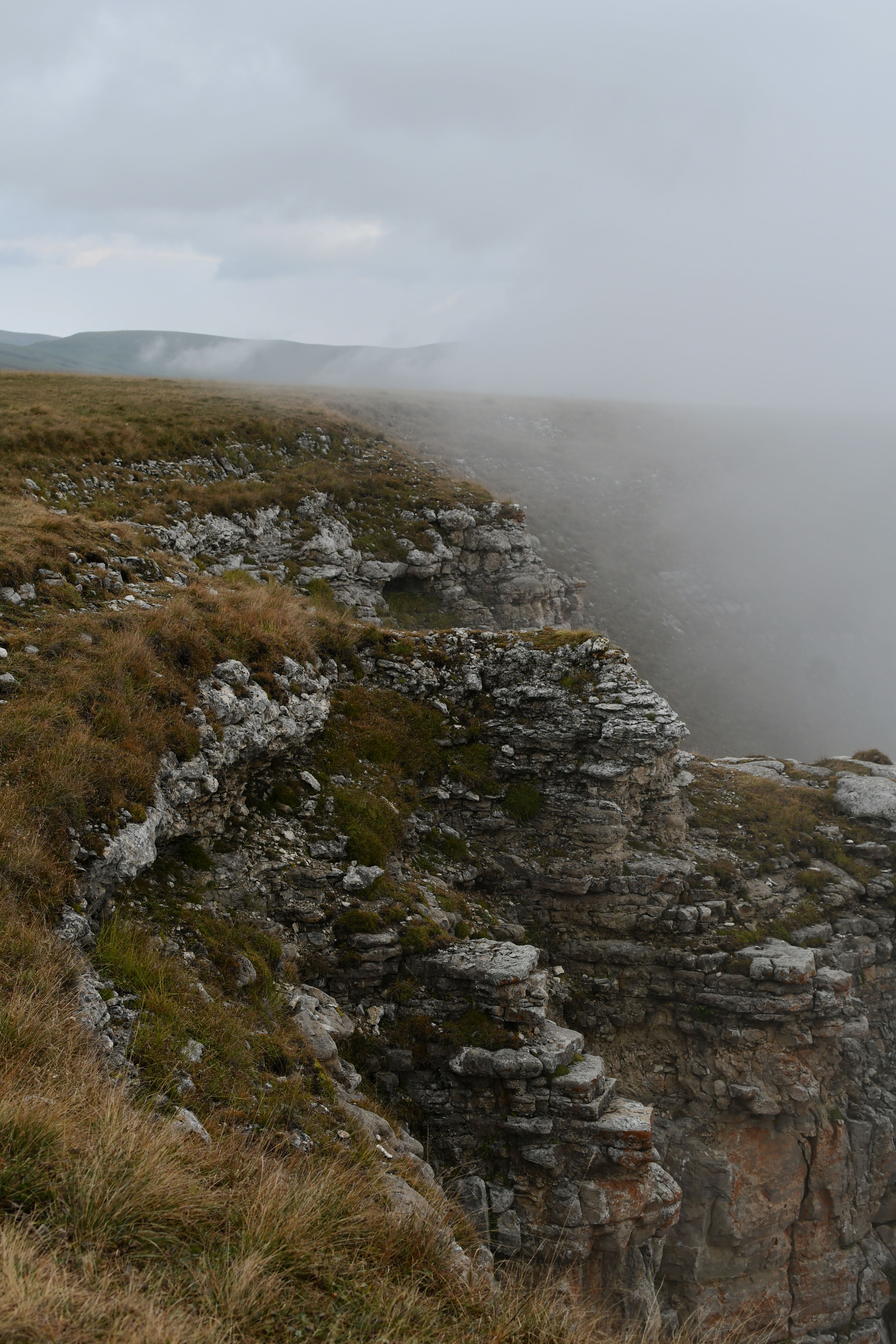 Atmospheric aerial view of misty cliffs and eroded rock formations amidst fog and nature