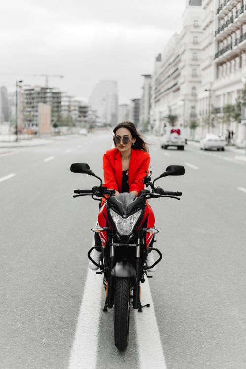 Free Fashionable woman in red with sunglasses riding a motorcycle in Baku, Azerbaijan. Stock Photo
