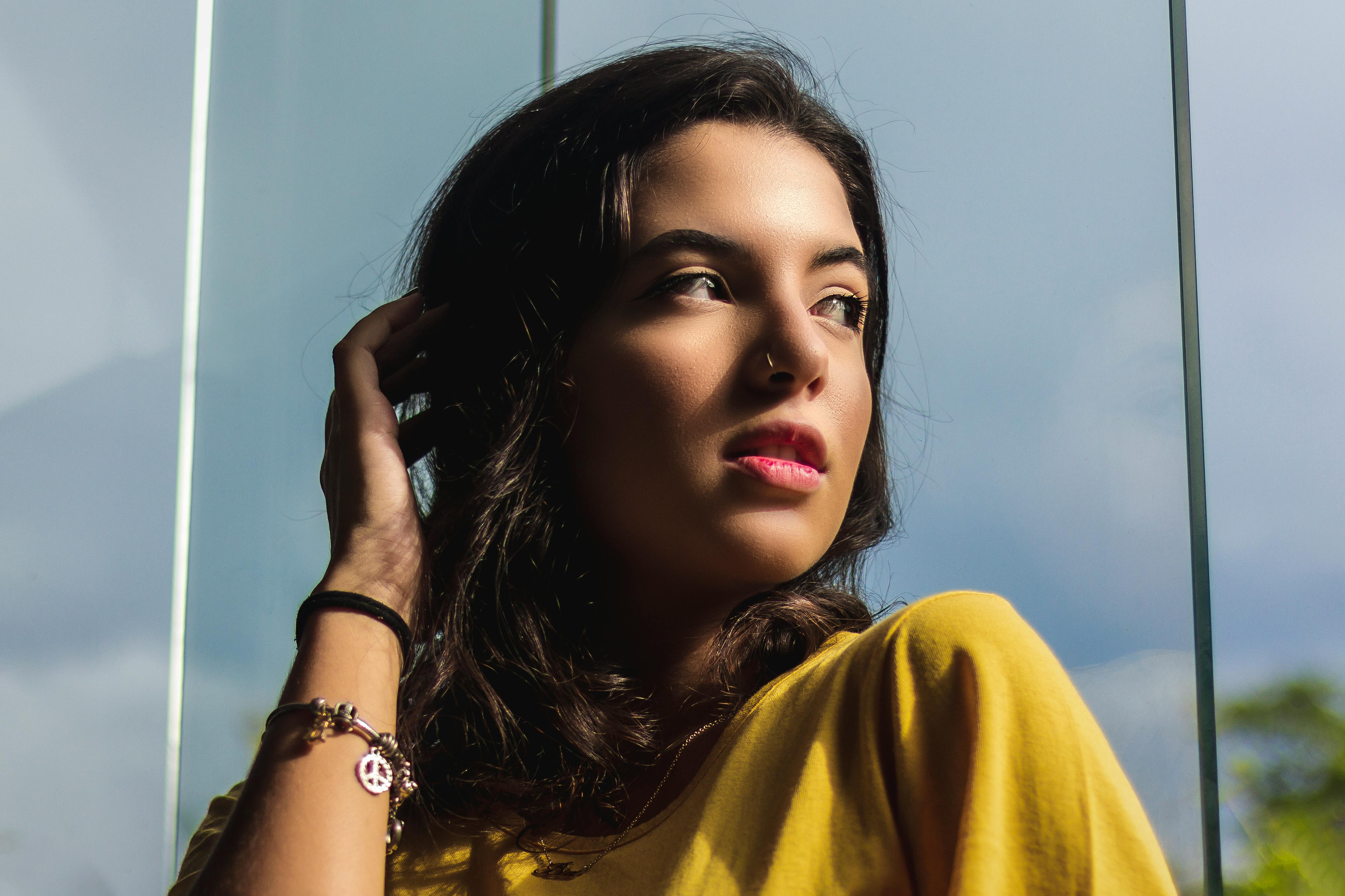 一位女性在窗前若有所思地摆出姿势，自然光下的特写肖像