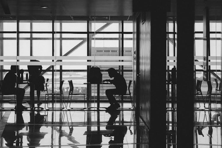 People Sitting By Tables At Airport Terminal