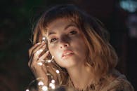 在柔和的肖像背景下，一名被串灯照亮的女子优雅地摆出姿势