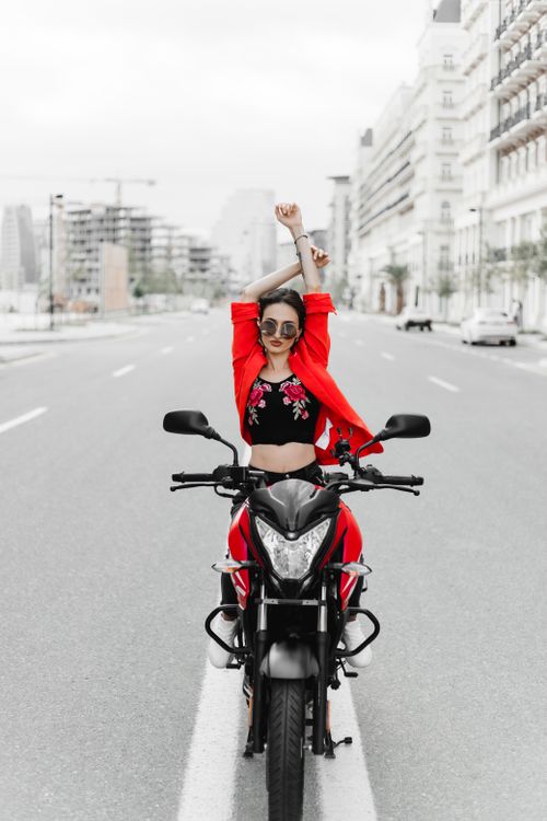 Free A stylish woman in a red outfit poses on a motorcycle on a city street in Baku, Azerbaijan. Stock Photo