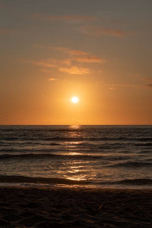 Free A stunning sunset over the ocean with vibrant sky colors reflected on the water's surface. Stock Photo