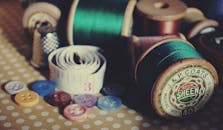 一系列复古缝纫用品，包括卷轴、纽扣和圆点桌布上的卷尺