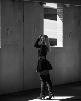 Black and white photo of a stylish woman posing indoors, showcasing fashion and elegance.