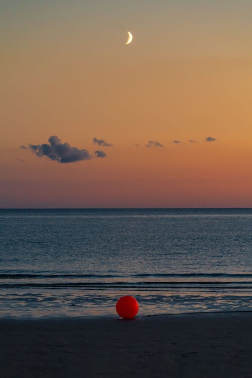 Red Buoy Lying on a Beach at Dusk