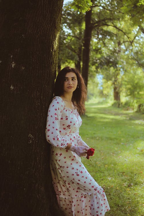 Beautiful Brunette Wearing a White Dress Leaning on a Tree