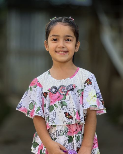 Free Cheerful girl smiling outdoors in colorful floral attire. Stock Photo