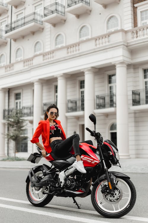 Woman in Red Suit Jacket Posing on Motorbike on Street
