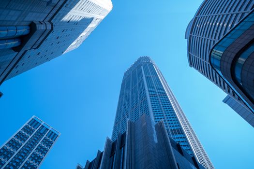 Low angle view of modern skyscrapers set against a bright blue sky, showcasing urban architecture.