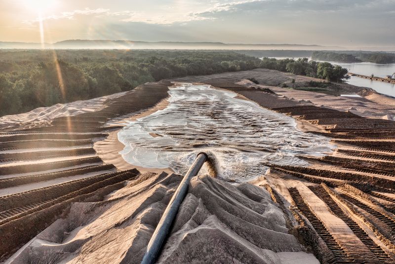 Drone shot of sand processing with flowing water and forest backdrop