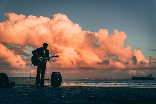 Man Playing Guitar on Beach at Sunset