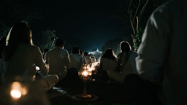 Silhouettes meditating in Borobudur's night gathering, Central Java.
