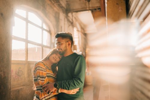 Free A loving couple hugs warmly under sunlight in a rustic indoor setting in Vadodara, India. Stock Photo