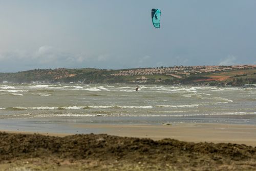 Free Exciting kitesurfing at a sandy beach with rolling waves and clear skies. Stock Photo