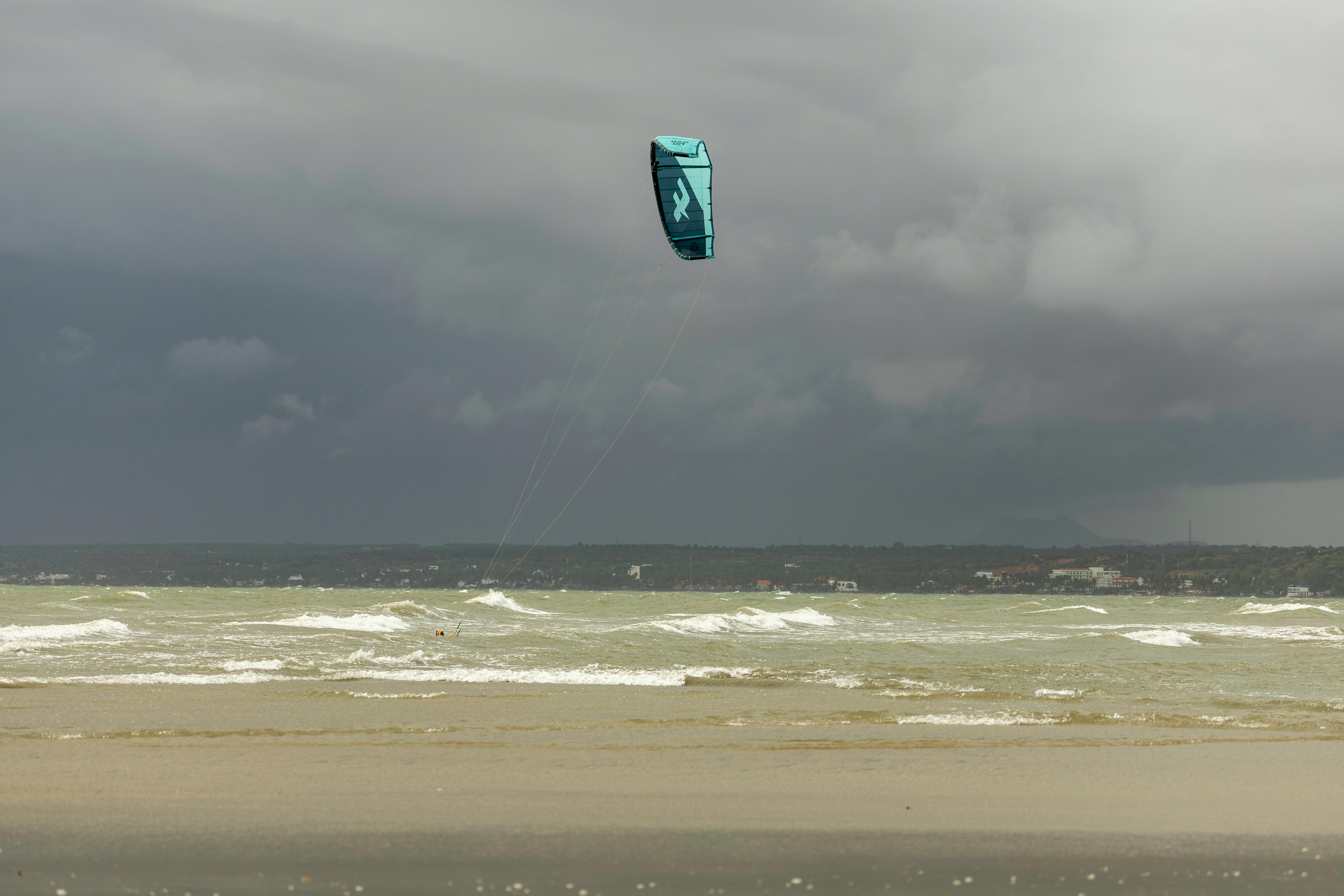 A kite surfer gliding across the sea under a cloudy sky, capturing the adventurous spirit of the ocean. (Photo: Serg Alesenko)
