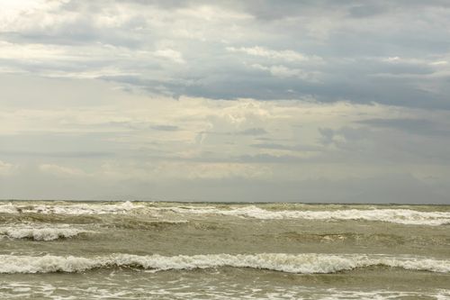 Free Tranquil seascape with waves crashing under an overcast sky, capturing nature's calm and power. Stock Photo