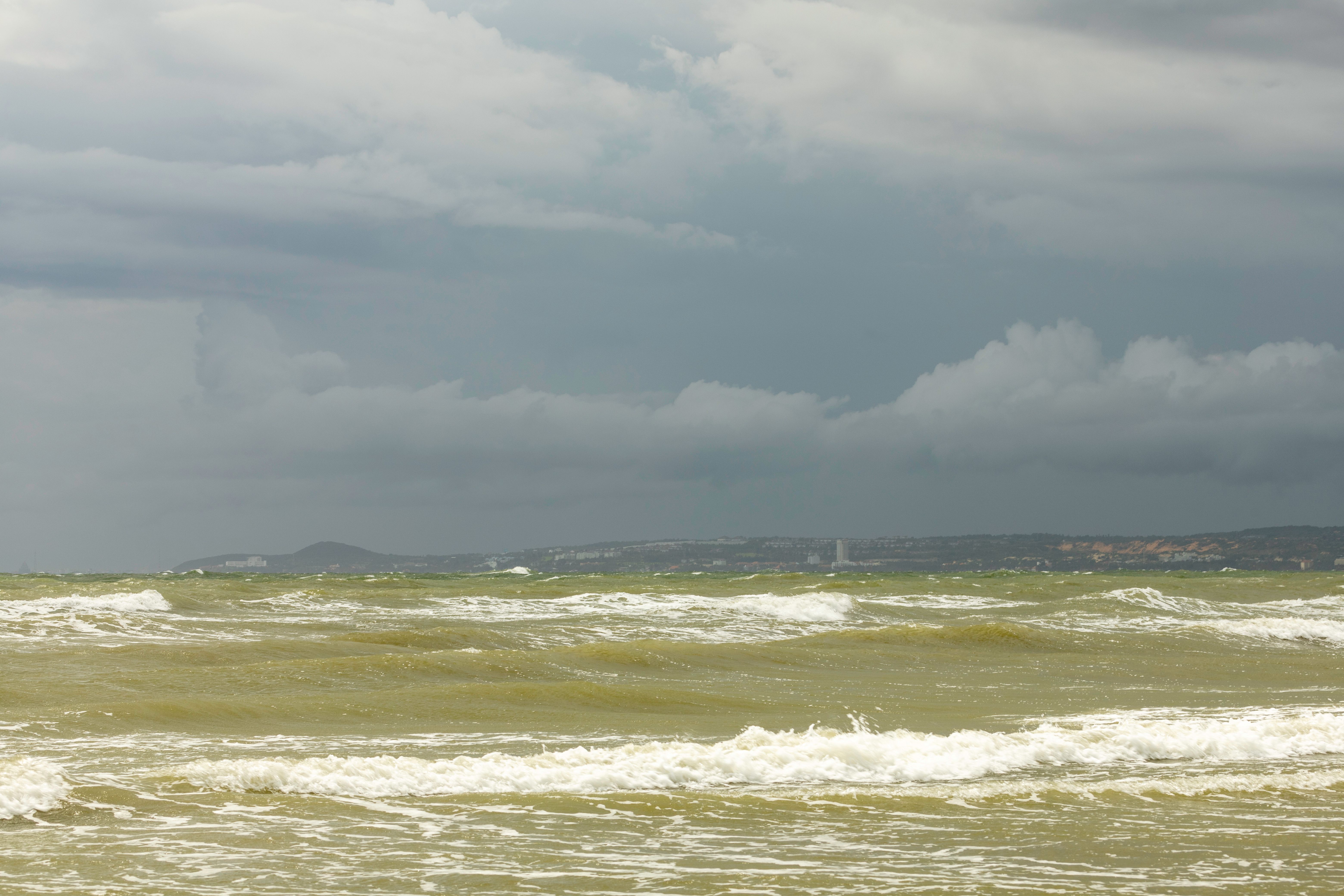 A captivating view of the ocean under a stormy sky. Turbulent waves and dark clouds create a dramatic seascape.