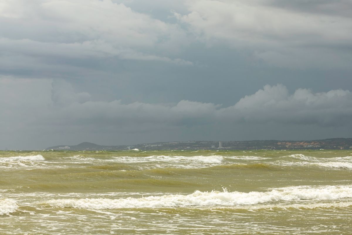 A captivating view of the ocean under a stormy sky. Turbulent waves and dark clouds create a dramatic seascape.