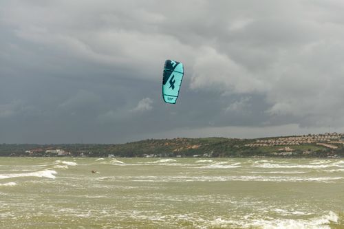 Free A dynamic kite surfing scene with vibrant blue kite against stormy sea and cloudy sky backdrop. Stock Photo