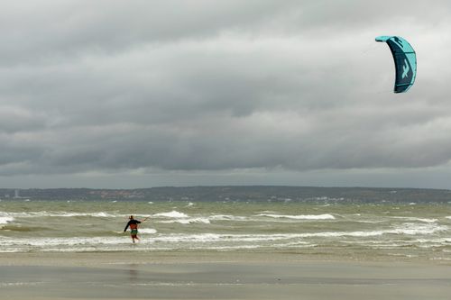 Free A kitesurfer navigates the choppy waves under a stormy sky on a scenic beach. Stock Photo