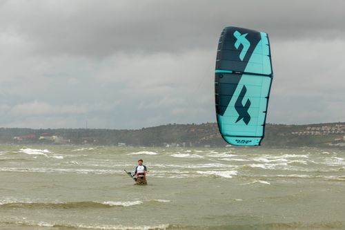 Free A person kitesurfing in the sea under cloudy skies, showcasing adventure and thrill. Stock Photo
