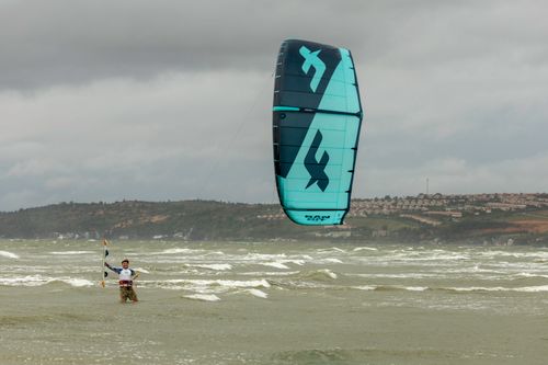 Free A kitesurfer enjoying the waves and wind near the coastline, showcasing skillful water sports. Stock Photo