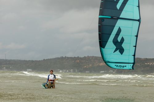 Free A kitesurfer enjoying a thrilling ride on the ocean waves under a cloudy sky. Stock Photo