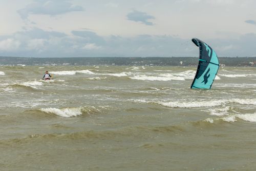 Free Experience the thrill of kitesurfing on the ocean's waves with a scenic view in the background. Stock Photo