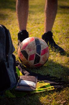 A soccer ball and backpack on grass, captured in warm sunlight, symbolizing outdoor sports activities.