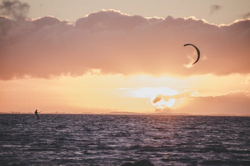 A Person Kitesurfing on the Sea at Sunset
