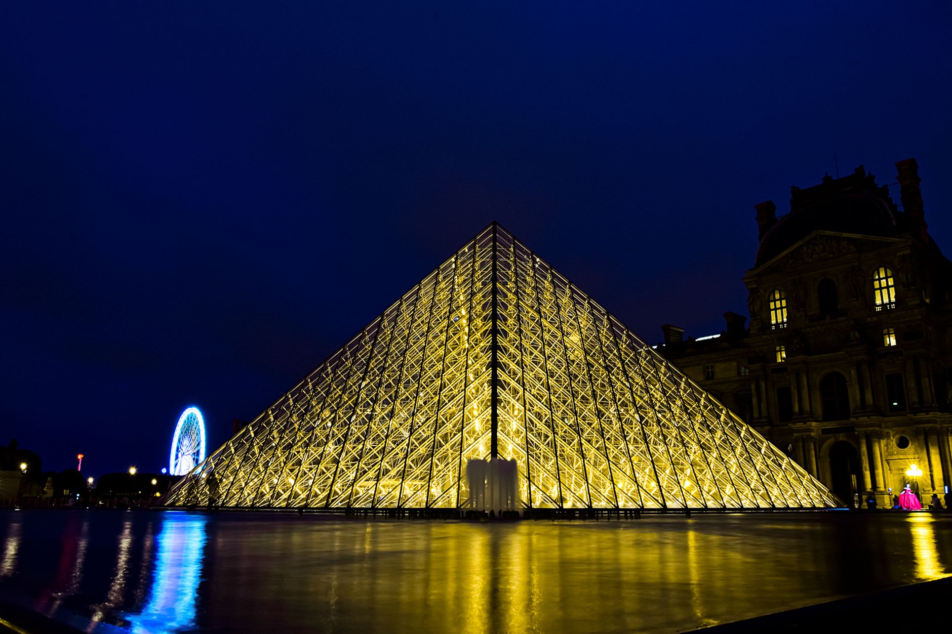 A stunning night view of the Louvre Pyramid in Paris illuminated with golden lights.