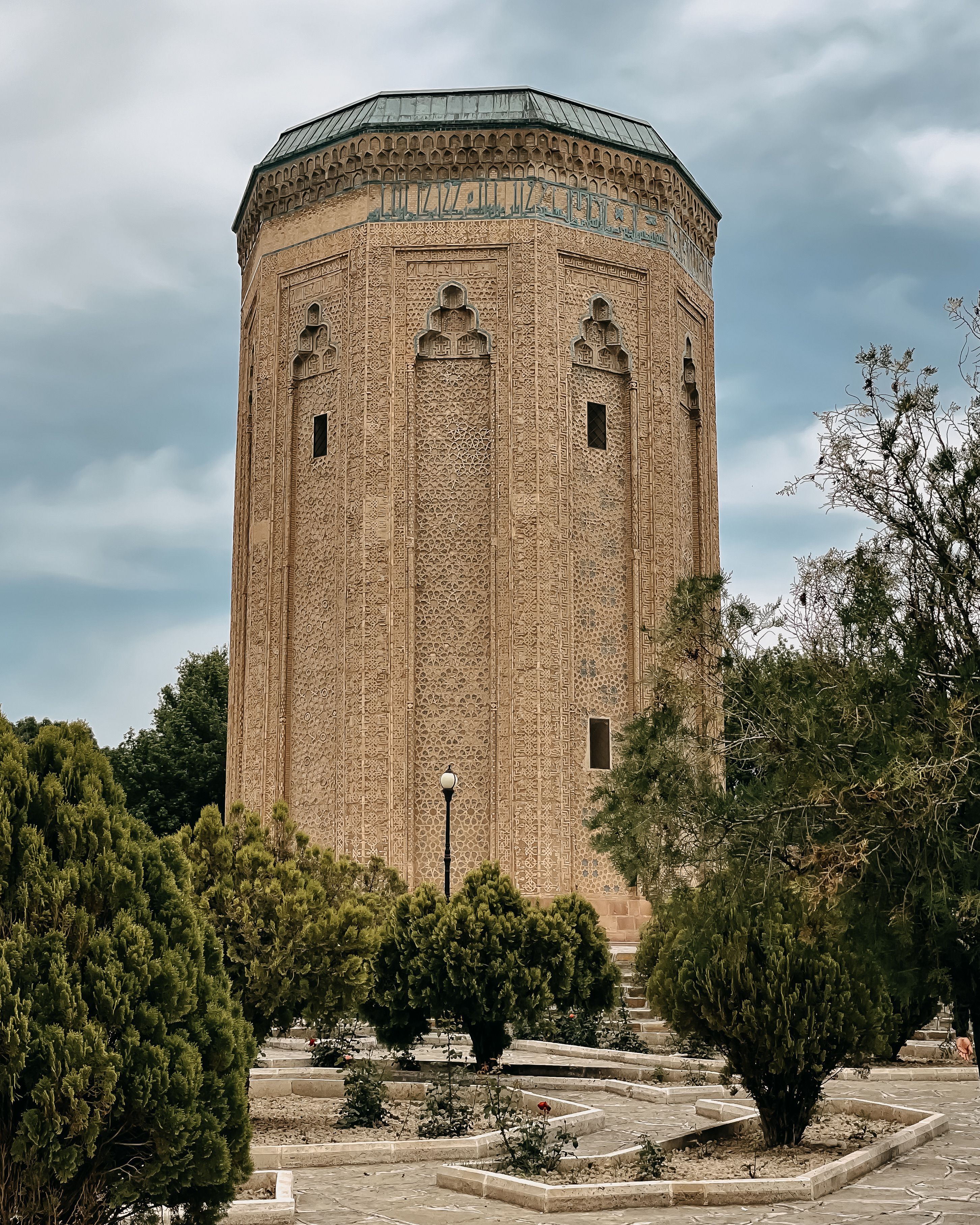 Discover the architectural beauty of the Momine Khatun Mausoleum in Nakhchivan with lush greenery surrounding it.