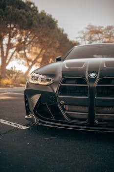 Close-up of matte black sports car parked on a scenic road with trees, captured at sunset in San Jose.