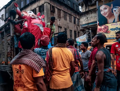 Free Group of men in Kolkata preparing Ganesha idol for festival on busy street. Stock Photo