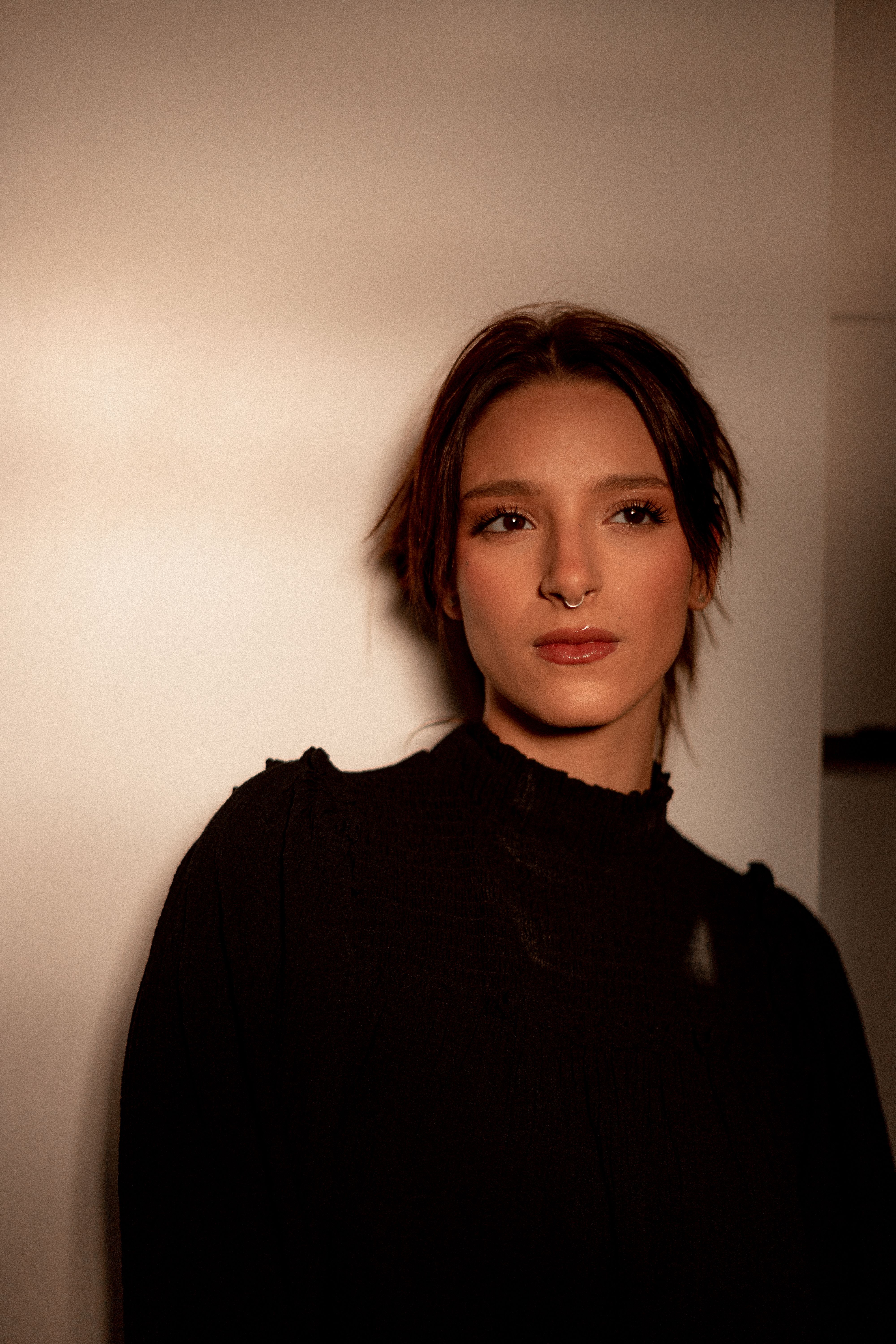 Portrait of a woman with brown hair, wearing black, in a neutral setting.