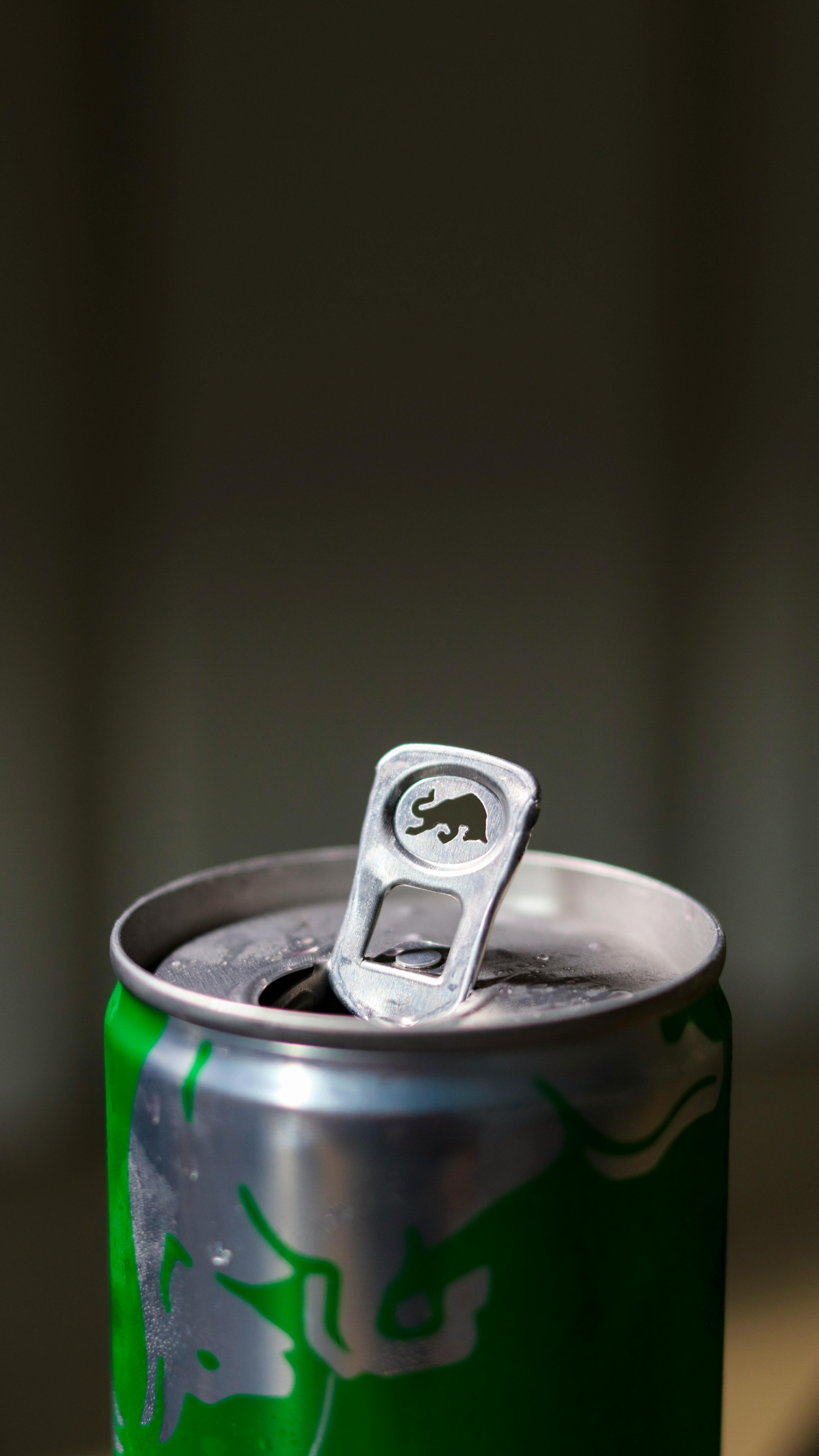 Detailed view of an open green aluminum energy drink can with a focus on the pull tab.