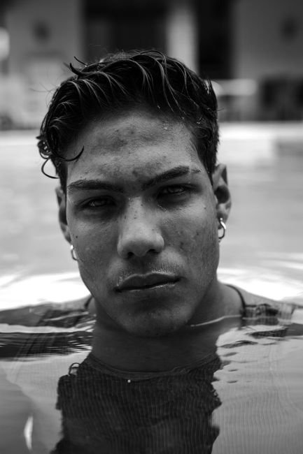 Monochrome close-up portrait of a man with wet hair, partially submerged in water, conveying intensity.