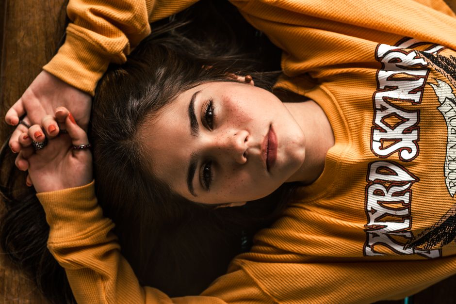 Close-up portrait of a woman lying down, wearing a casual yellow sweater.