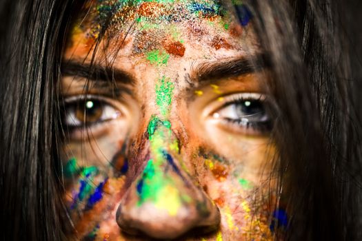 A striking close-up of a woman's face covered in vibrant, colorful paint, capturing artistic expression.