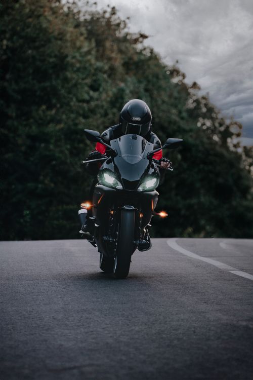 Free A biker with a helmet rides a motorcycle on a winding road. Stock Photo