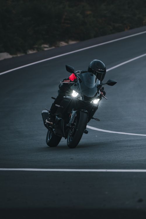 Free Dynamic shot of a motorcyclist leaning into a curve on a winding road, captured in daylight. Stock Photo
