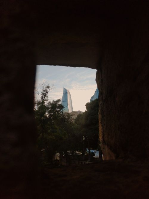 Free View of Flame Towers in Baku framed by ancient stone walls, capturing a blend of old and new architecture. Stock Photo